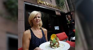 Sarma Melngailis holding a plate of food in front of a Pure Food and Wine restaurant in New York